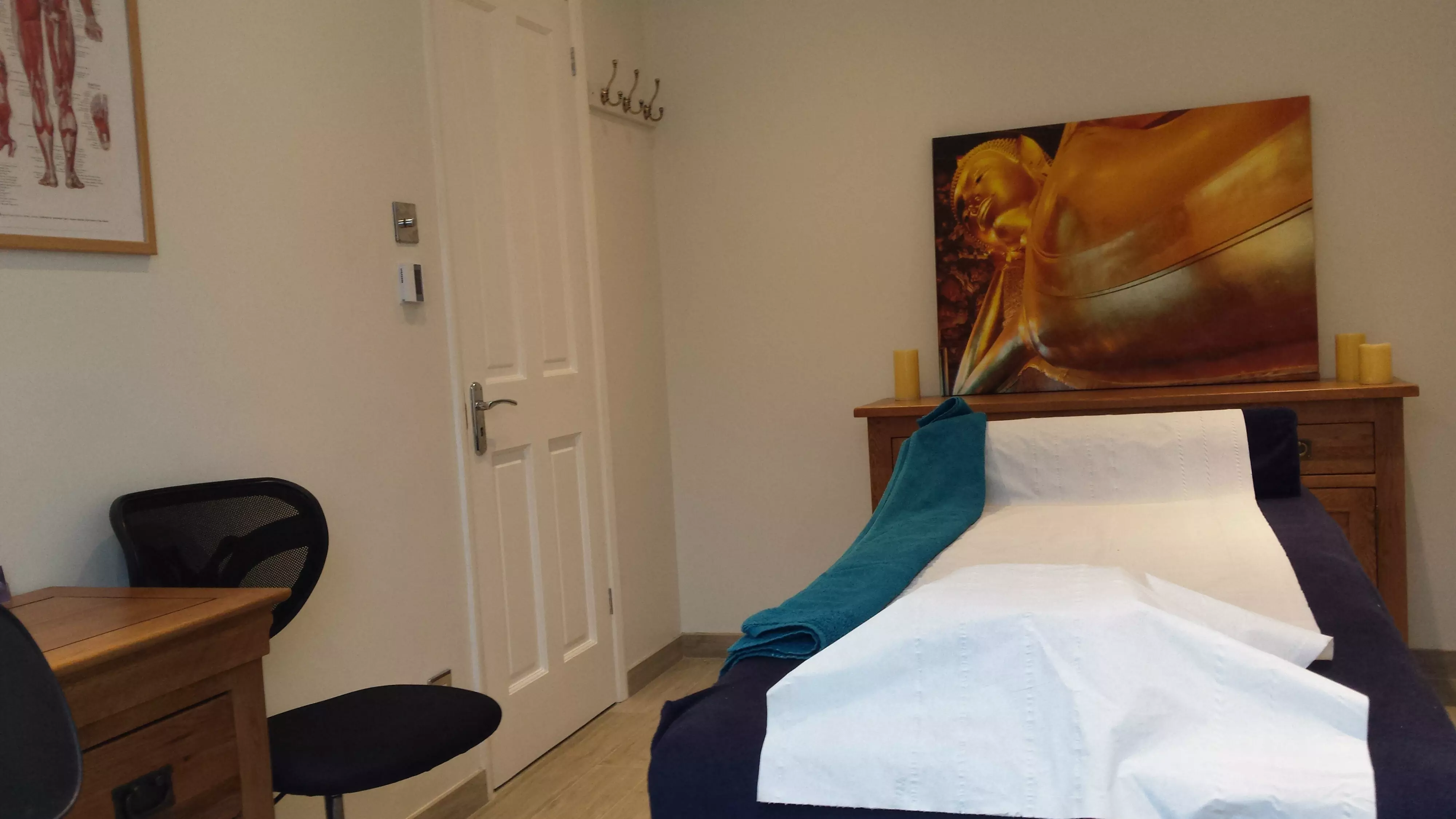 Interior of the East Dulwich clinic, showing a small wooden desk, two chairs and a couch, in a clean harmonious environment.
