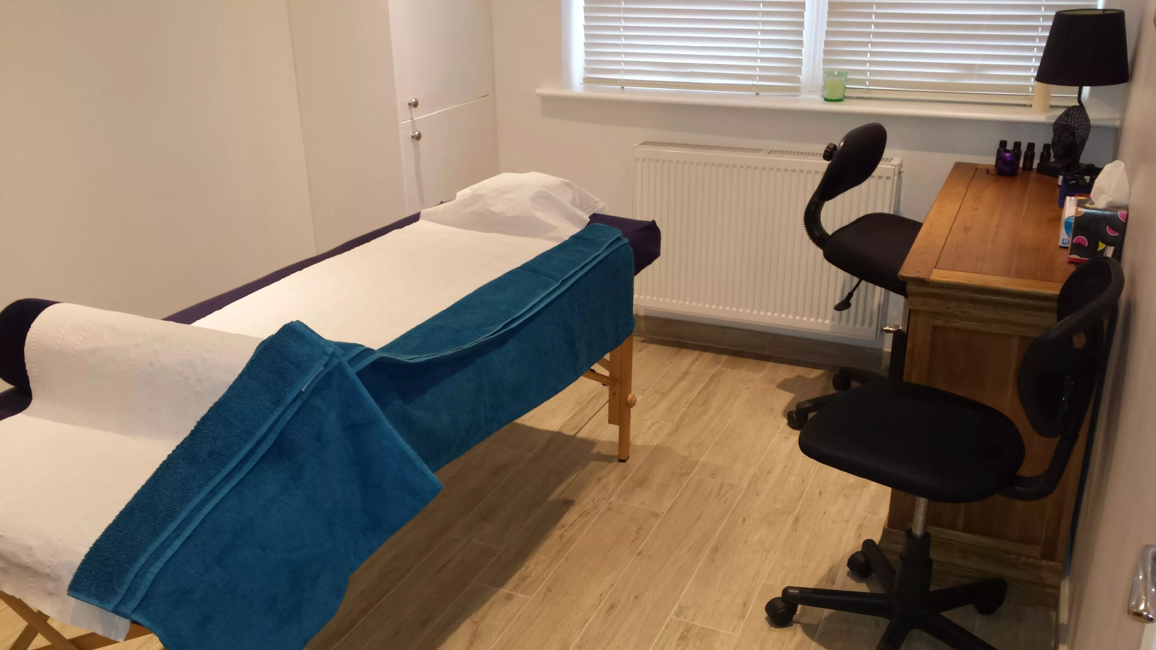 Interior of the East Dulwich clinic, showing a small wooden desk, two chairs and a couch, in a clean harmonious environment.