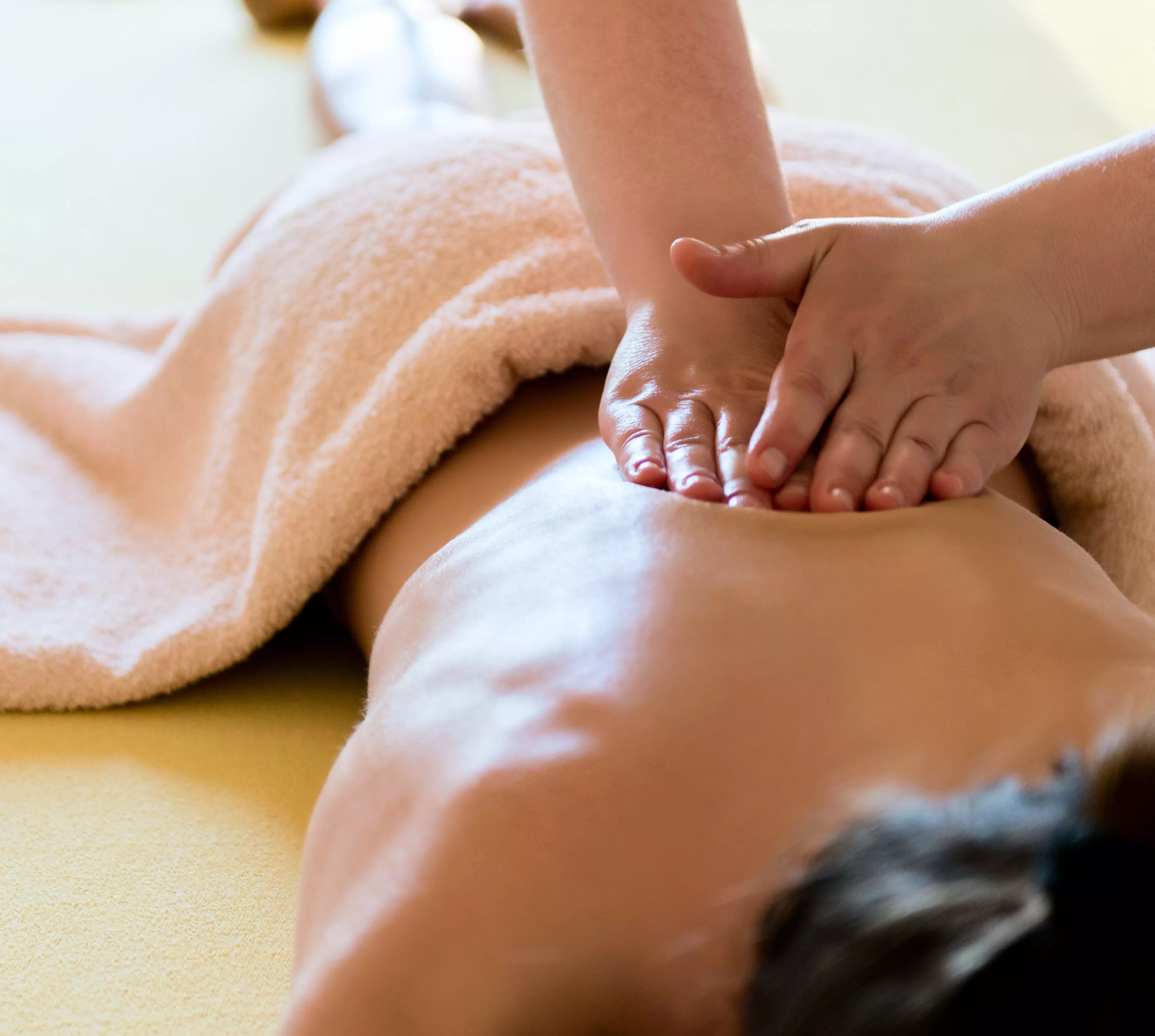 therapist massaging the back of a pregnant woman who is laying on her side on a massage couch