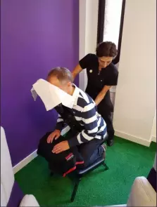 On site treatments in companies. Life Massage therapist, shown while treating a person on a massage chair in a company on site.