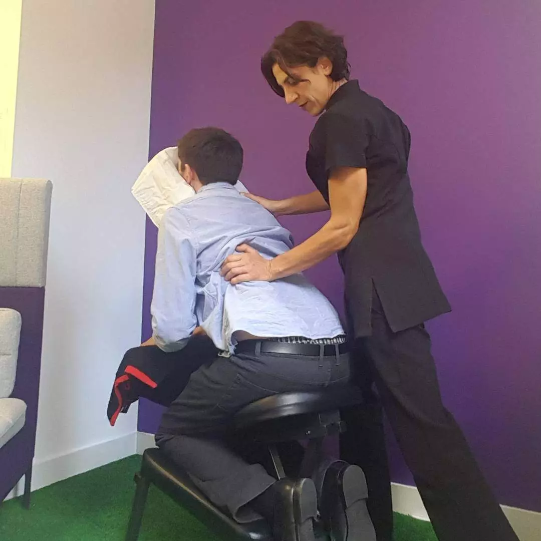 Seated massage treatment with therapist working on client's back on-site