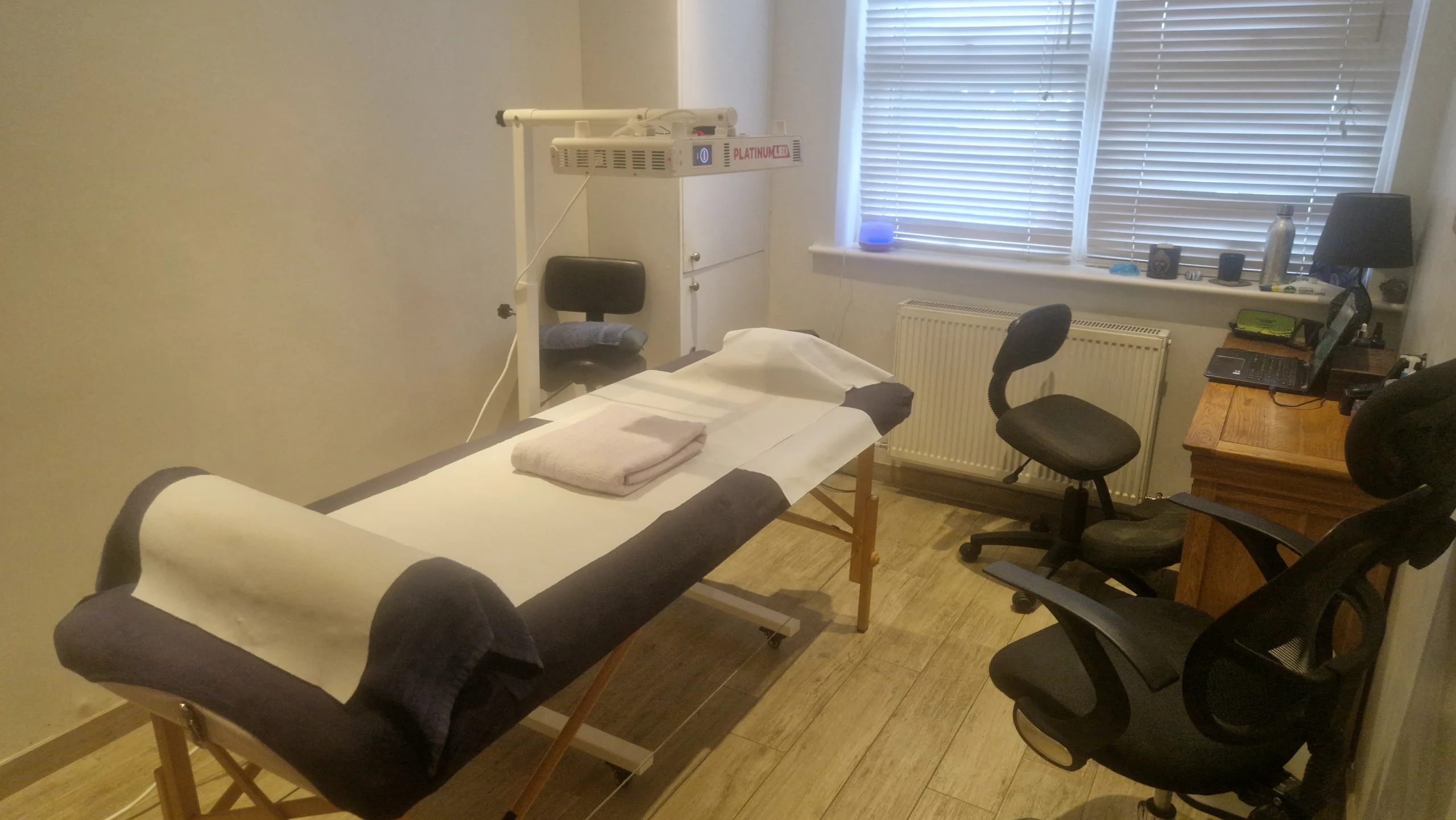 Infrared and red light therapy treatment room in East Dulwich with BioMax panel and massage couch.