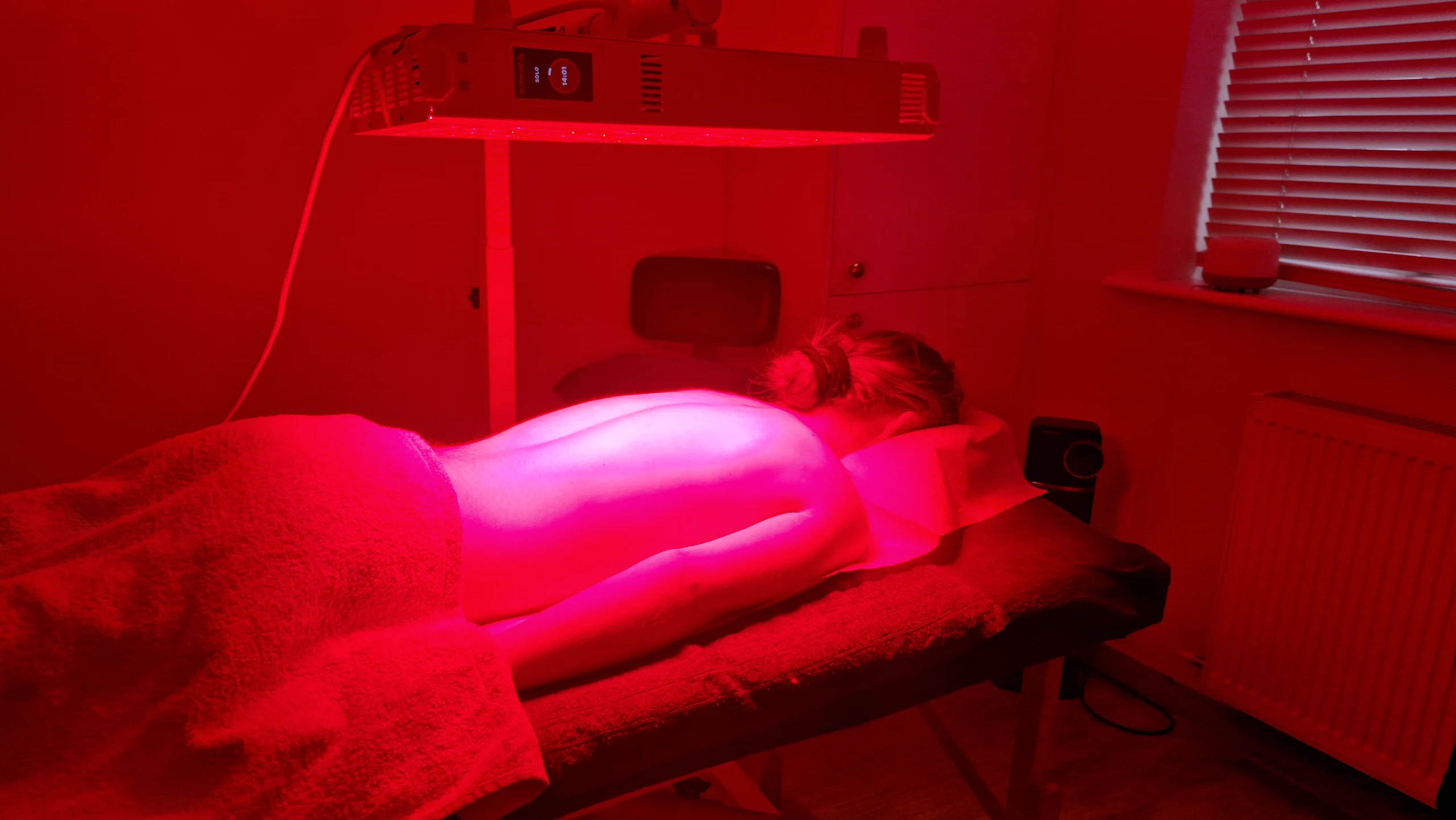 Side view of red light therapy session using medical-grade LED panel.